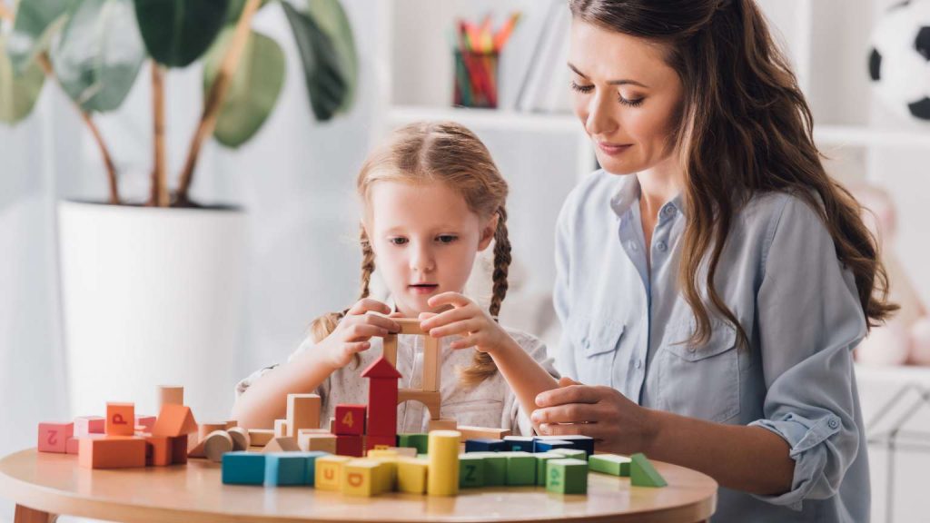 Mamá e hija jugando con bloques en casa con juguetes para niños