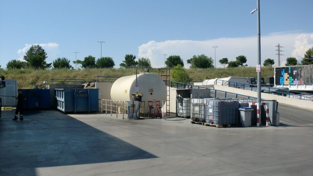 "Zona industrial con depósito de combustible y contenedores, instalaciones que requieren licencia ambiental en Barcelona"