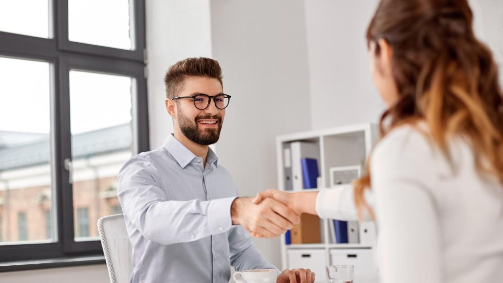 Executive search firm interview handshake between recruiter and candidate in modern office
