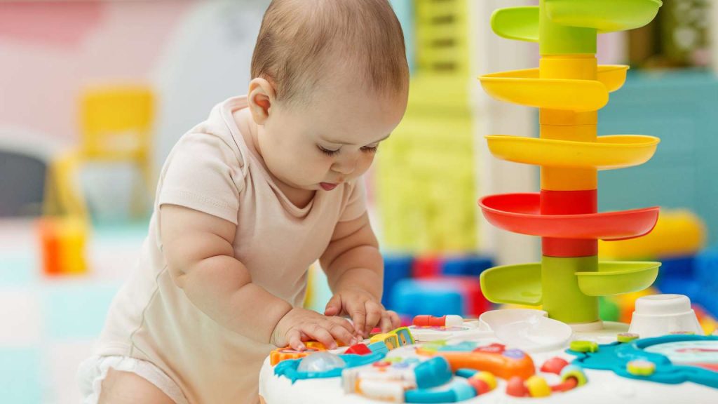 Bebé explorando texturas con juguetes para niños pequeños durante una actividad sensorial en casa