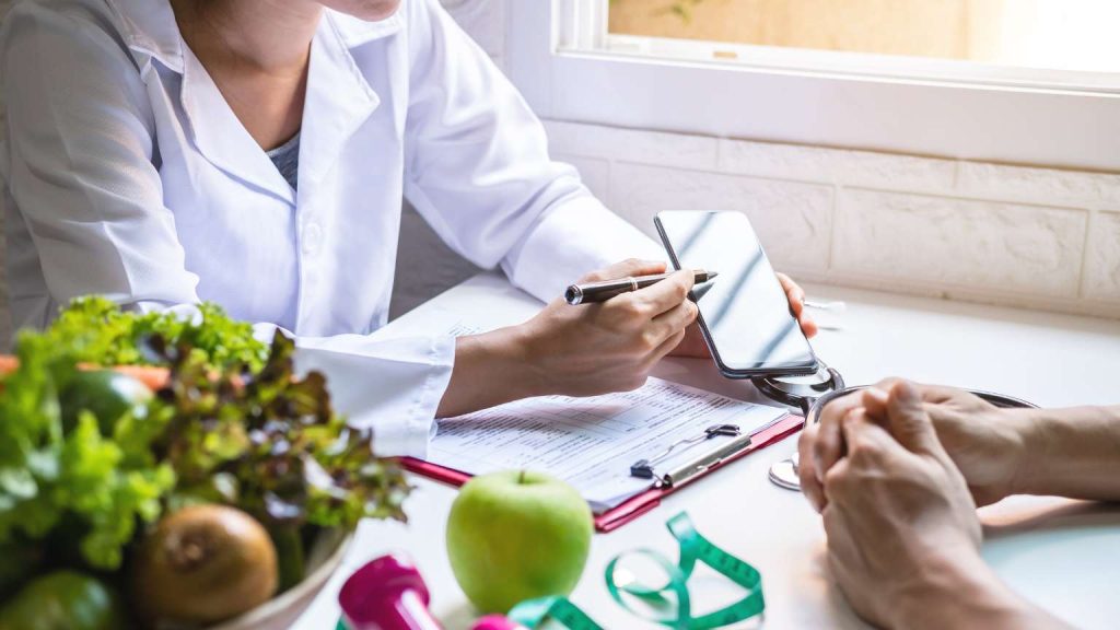 Nutricionista asesorando a un paciente en consulta, ambos sin mostrar el rostro, en un entorno cálido y profesional, abordando la inflamación silenciosa.