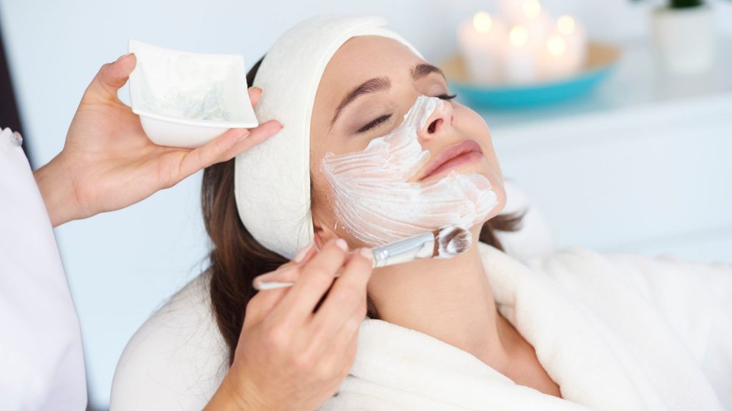 Mujer relajada recibiendo limpieza facial profunda por esteticista en Barcelona.