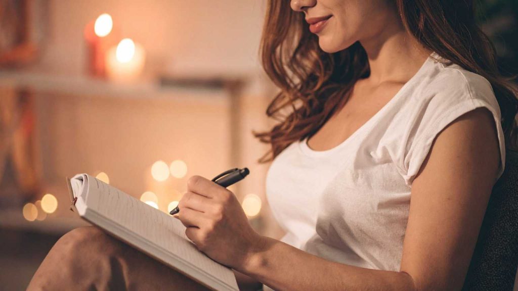 Mujer en Valencia escribiendo en su diario en un espacio tranquilo que promueve el bienestar emocional, ejemplo de cómo los pequeños hábitos impactan en la salud mental.