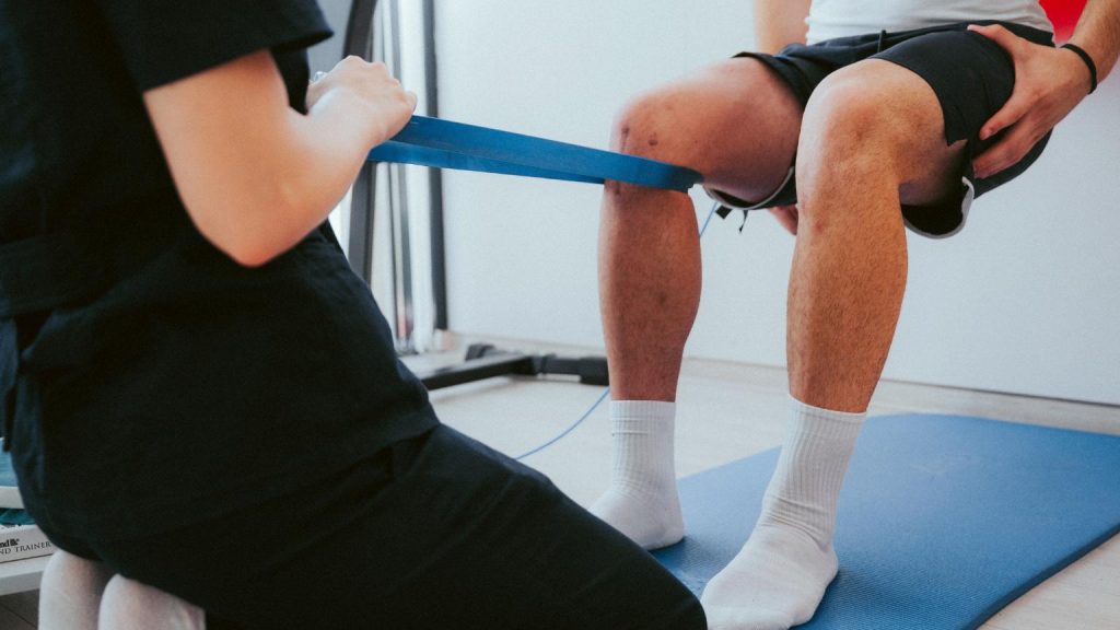 Centro de fisioterapia realizando ejercicios de rehabilitación de rodilla con banda elástica