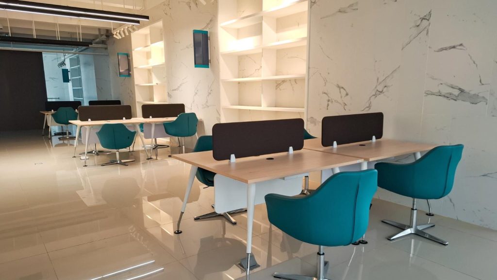 Espacio de coworking en Sevilla moderno con puestos compartidos, sillas ergonómicas y diseño minimalista en tonos claros.