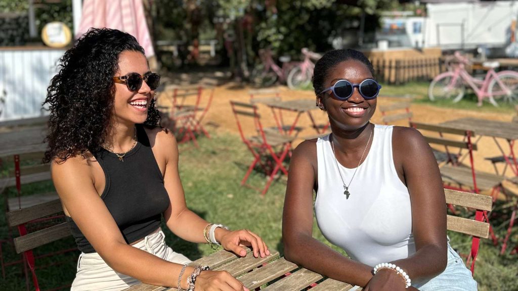Dos mujeres al aire libre luciendo gafas modernas mientras conversan con estilo relajado