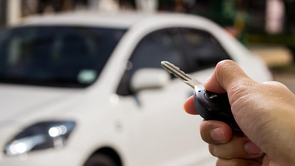 Persona sosteniendo la llave de un coche al revisar vehículos usados antes de comprar