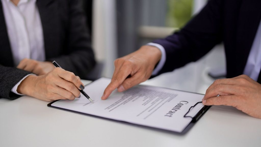 Asesor legal guiando la firma de un contrato durante una consulta sobre trámites de extranjería.
