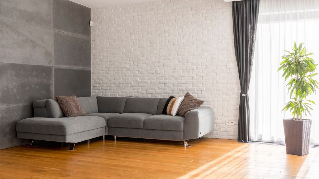 Sofá gris con almacenaje en salón moderno con luz natural y decoración minimalista