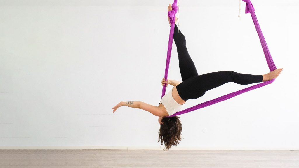 Aerial fitness training with a person practicing aerial exercise suspended on fabric