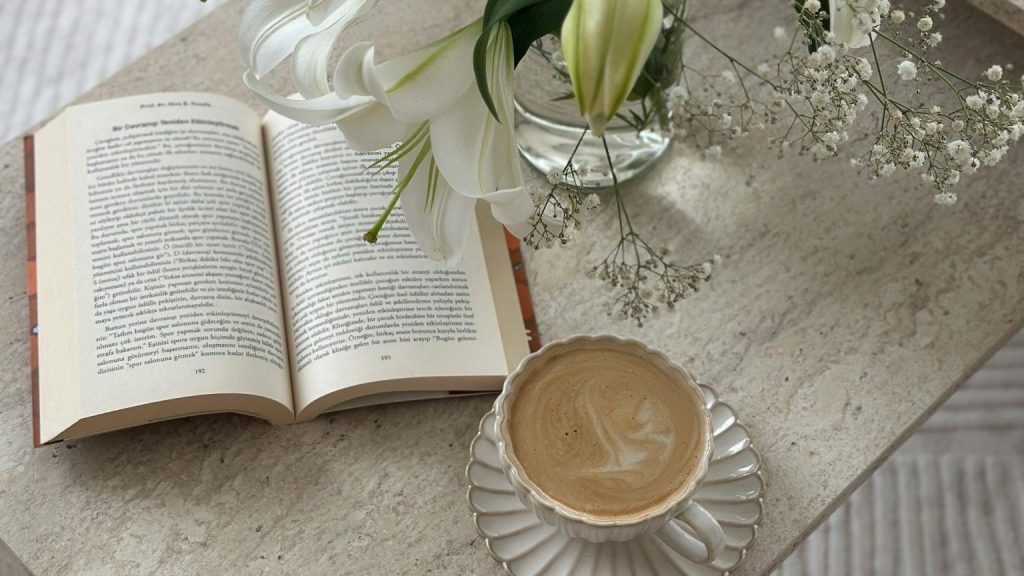 Libro abierto junto a café y flores, ideal para leer una novela romántica histórica con calma.