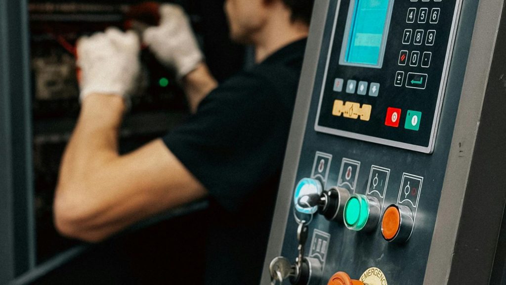 Técnico revisando maquinaria y panel de control de equipamiento comercial para negocios, instalación y mantenimiento profesional