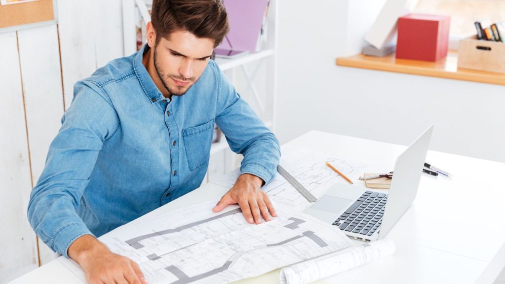 Ingeniero revisando planos técnicos en una oficina moderna, simbolizando el proceso de obtención de licencias de actividad en Barcelona