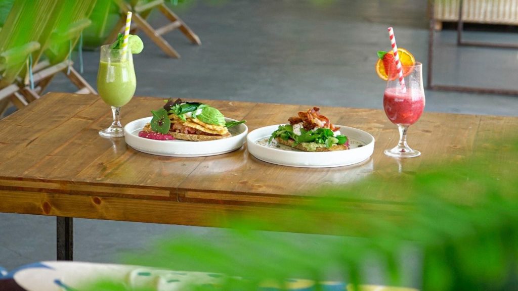 Platos de brunch y smoothies servidos en Banana Beach Club sobre mesa de madera en un restaurante de playa con ambiente relajado