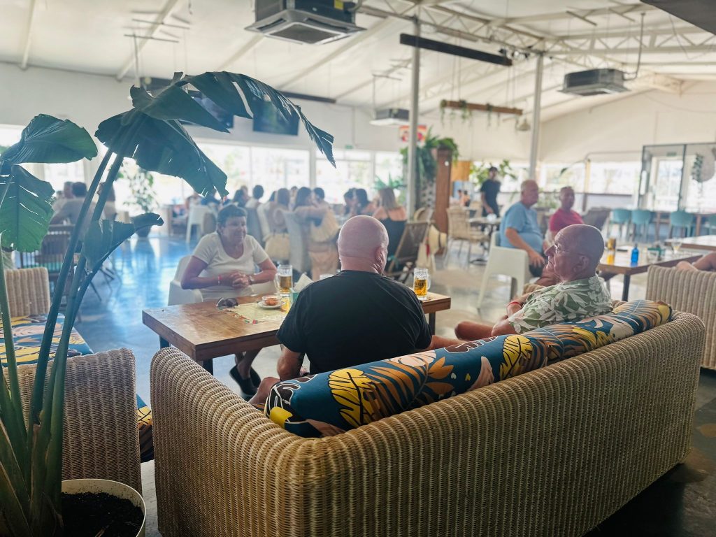 Ambiente interior de Banana Beach Club con turistas y residentes disfrutando de un restaurante relajado y social durante el día