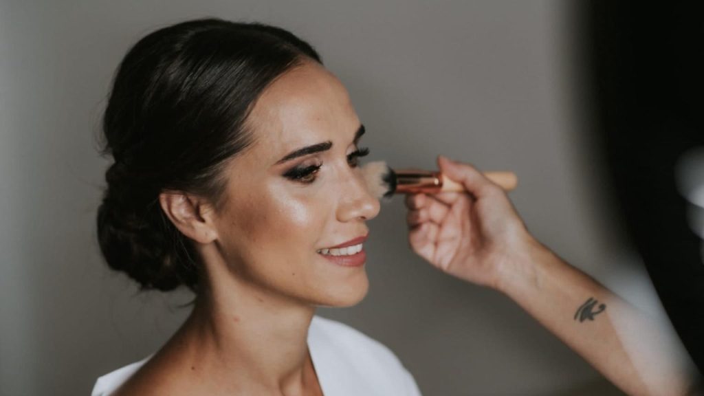 maquilladora profesional aplicando maquillaje a una mujer para evento con acabado natural y luminoso